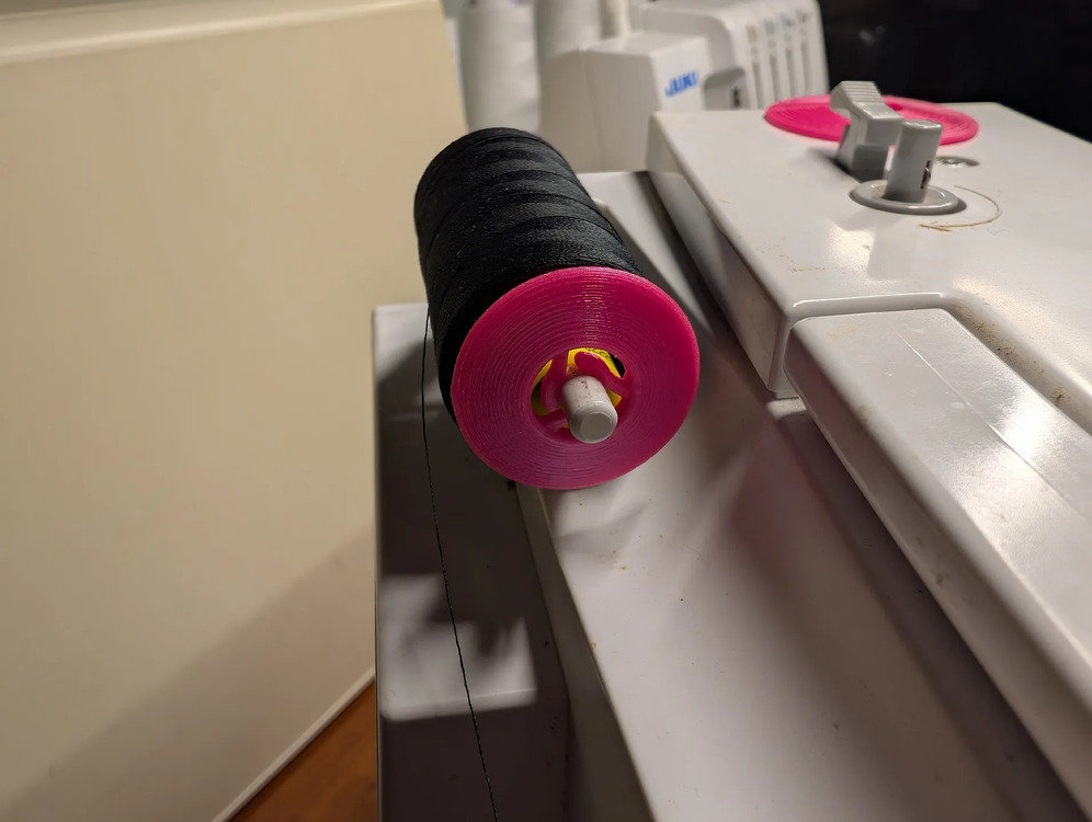 Spool pin cap installed on a thread spool on a serger
